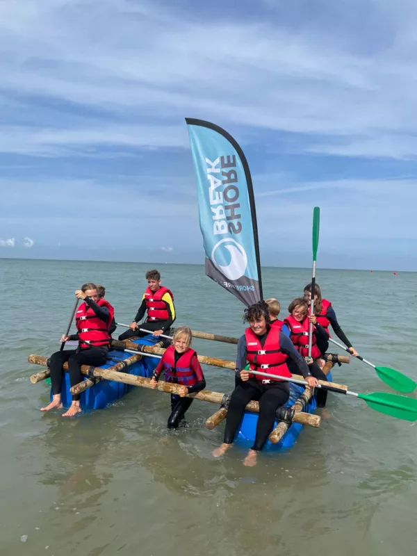 De kinderen testen hun zelfgemaakt vlot op een dag zonder golven.