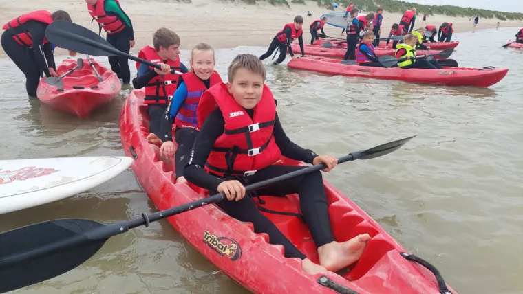 Kajakken op surfkamp in Oostduinkerke - Blije kinderen tijdens het kajakken op zee. - Surfkampen
